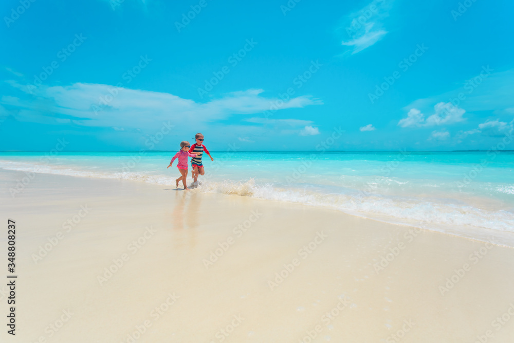 happy little girl and boy run and have fun on beach