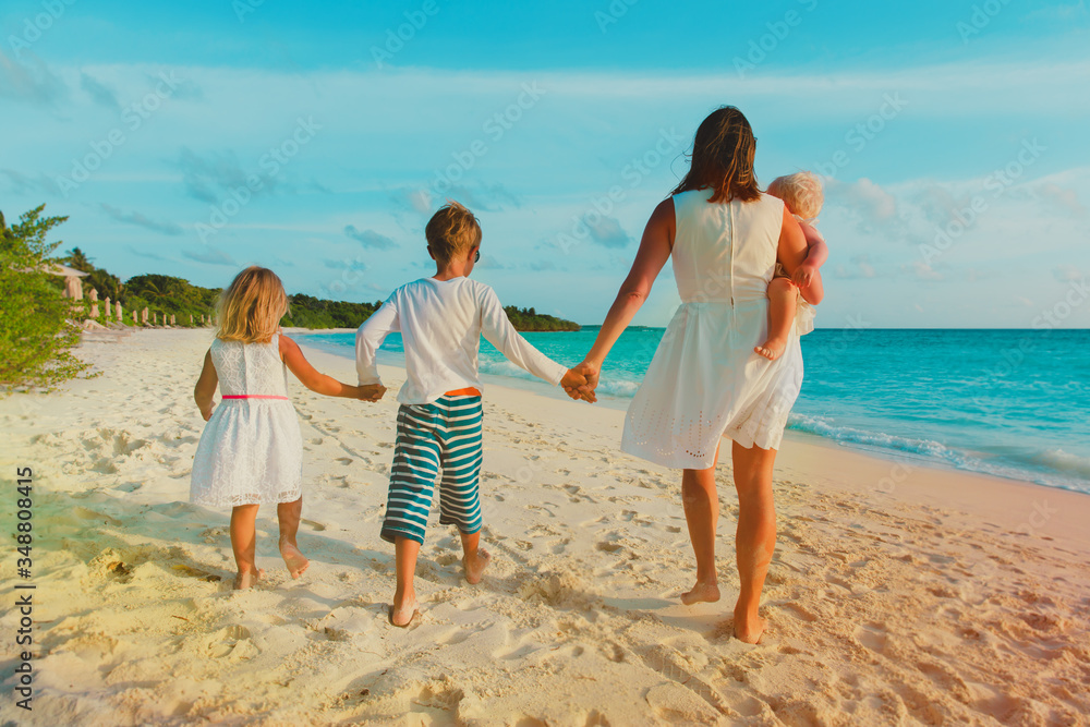 mother with kids walk on beach, family at sea