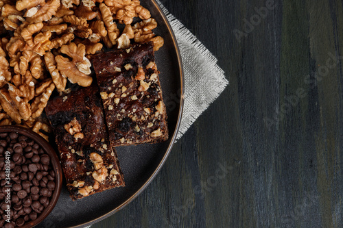 chocolate and walnut brownie next to walnuts and chocolate photo