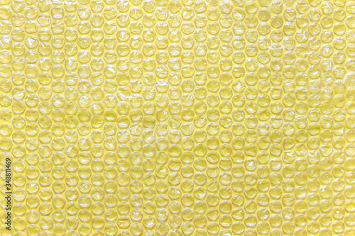 Yellow bubble wrap air filled transparent packaging foil placed on yellow backgound.
