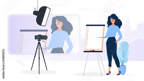 The girl is giving a presentation in front of the camera. The teacher conducts a lesson online. The concept of blogs, online training and conferences. Camera on a tripod, softbox.