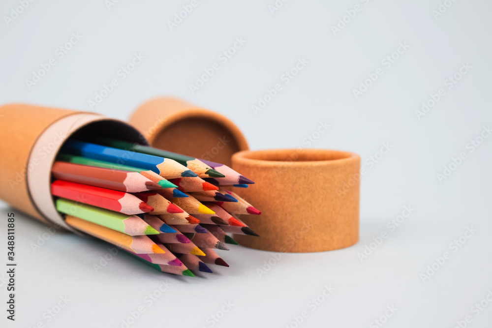 Fototapeta premium Close up of paper tubes with color pencils inside on light grey background with copyspace. Reusable packaging and recycling concept showing how to reuse cardboard packaging at home. Mockup