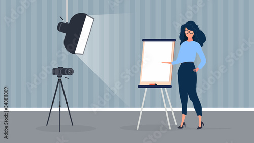 The girl is giving a presentation in front of the camera. The teacher conducts a lesson online. The concept of blogs, online training and conferences. Camera on a tripod, softbox.
