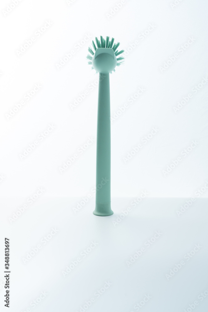 A green brush is placed on a white background. Kitchen dishwashing brush on white background. A green brush is placed on a white background. Kitchen dishwashing brush on white background.