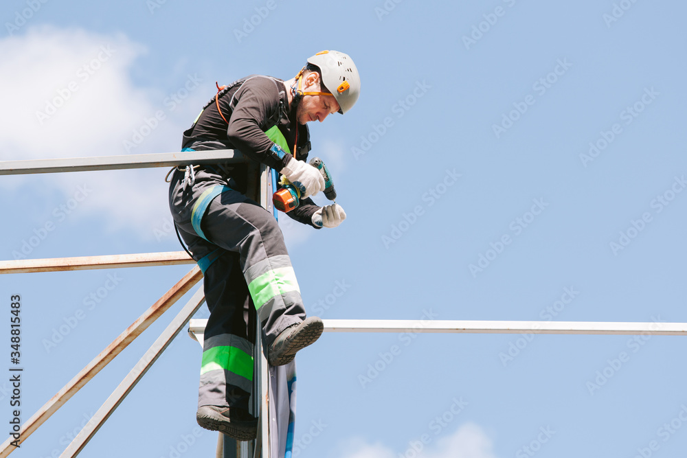 Industrial climber in helmet and overall working on height. Risky job. Professional worker Industrial climber in helmet and overall working on height. Risky job. Professional worker