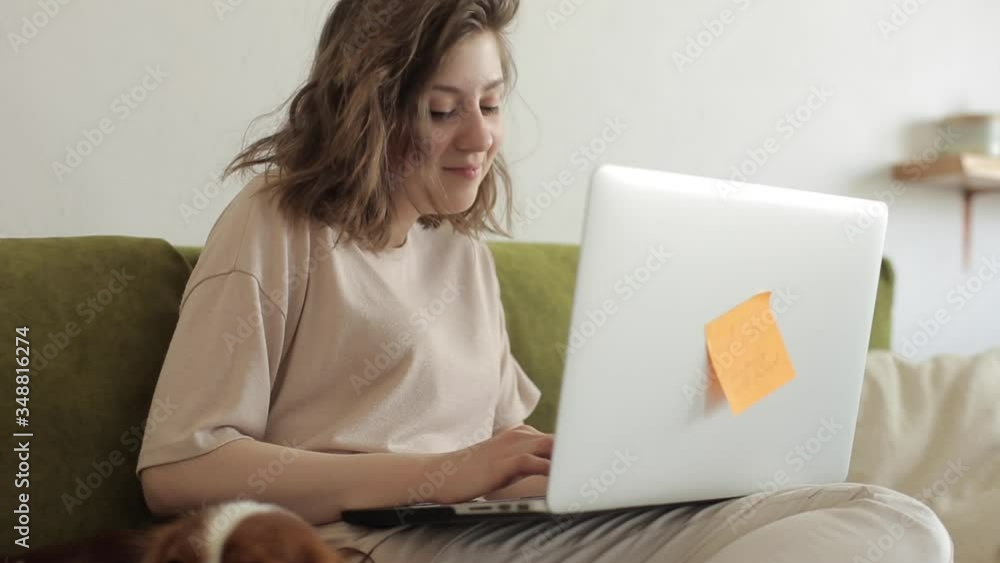 Young beautiful girl freelancer is working on a laptop while sitting at ...