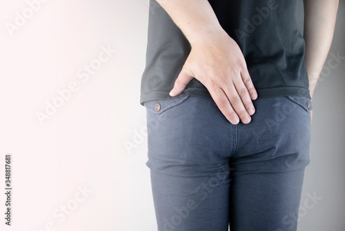 A man holds his hands to the ass feeling pain. Conversion of pain in the rectum, hemorrhoids and pain in the excretory system of the body. Frequent bowel movements.