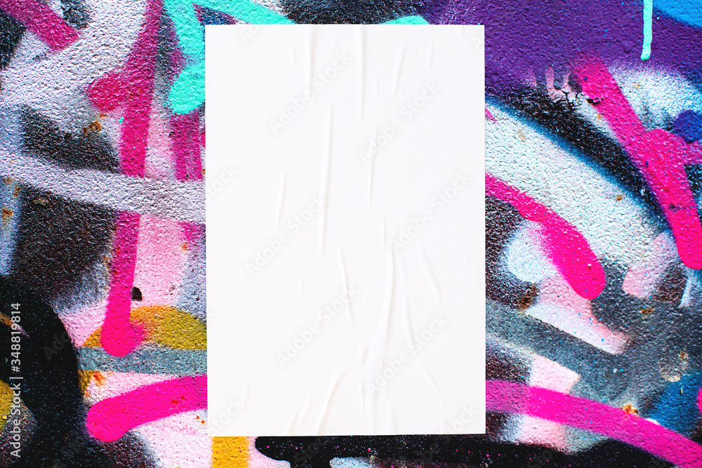 Naklejka premium Closeup of colorful messy painted urban wall texture with wrinkled glued poster template . Modern mockup for design presentation. Creative urban city background. 