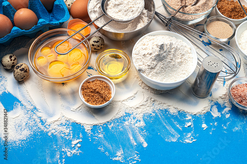 Baking ingredients on blue color background, top view