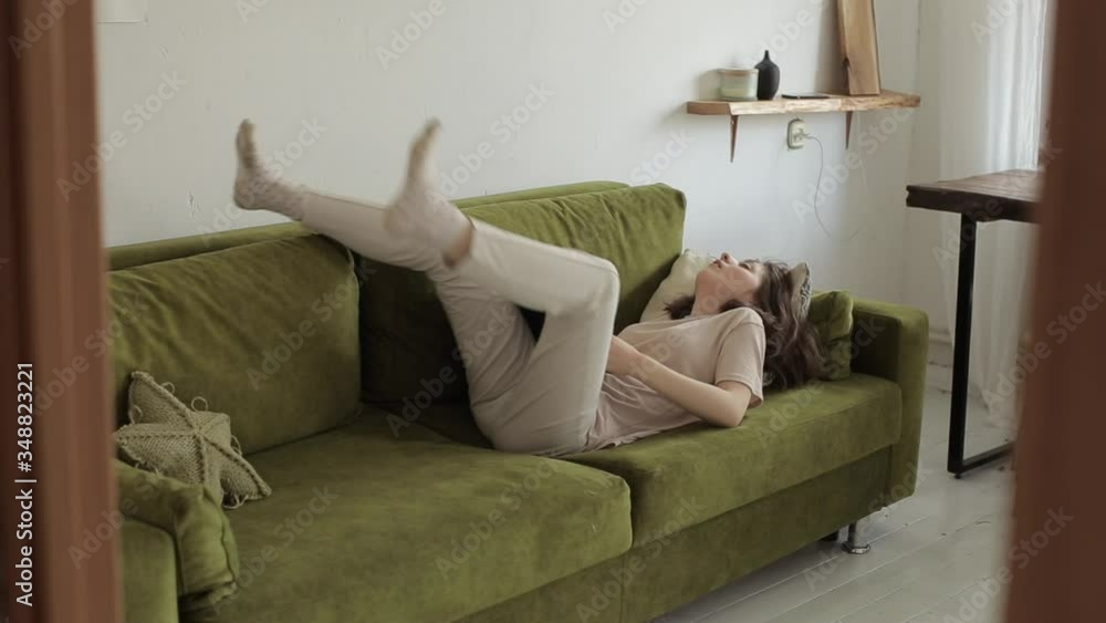 A young freelancer girl works on a laptop lying on a sofa and wearily closes it and leaves the room. Close-up A young freelancer girl works on a laptop lying on a sofa and wearily closes it and leaves the room. Close-up