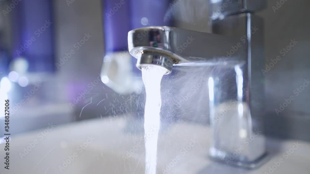 Steam from hot water in the sink. Hot tap water. Warm water flows from the tap in the bathroom