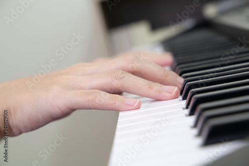Closeup of hands playing piano lateral view. Selective focus. Hobby during staying at home. 