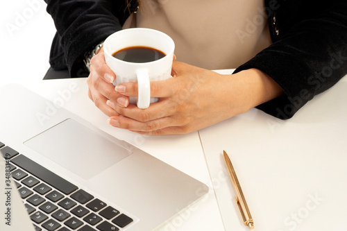 A businesswoman holding a cup of coffee in her hands while she is working