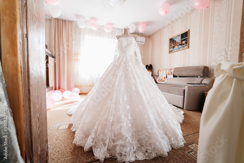 A white wedding dress is worn on a mannequin in the middle of the room © ANDREY