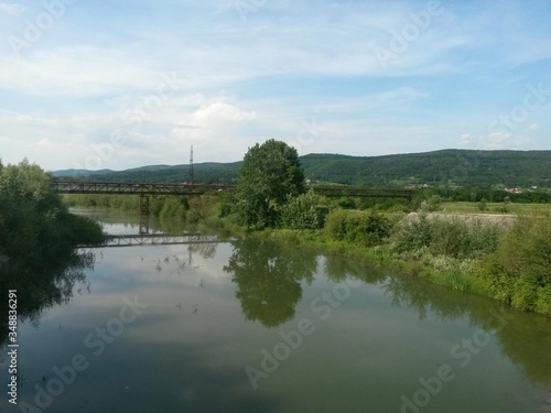 Obraz na płótnie lake reflecting green forest close to the woods in summer season on sunny day with blue sky w salonie