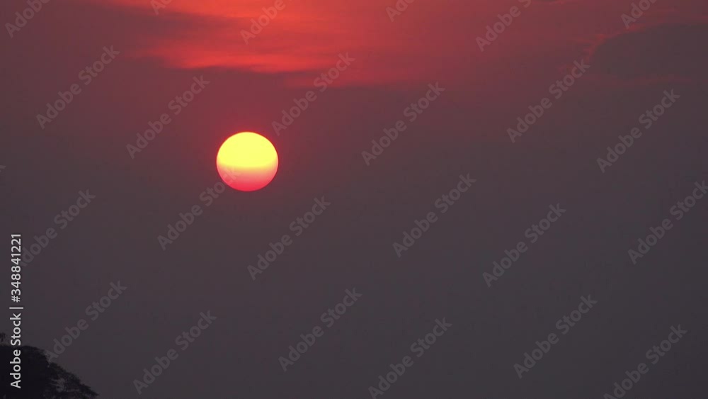 Timelapse of the Blood Red Disk of the Sun Setting Behind the Clouds and Over the Horizon Timelapse of the Blood Red Disk of the Sun Setting Behind the Clouds and Over the Horizon