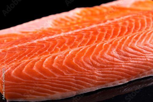 Uncooked fish fillet isolated on black. Raw salmon fillet. Closeup, macro view