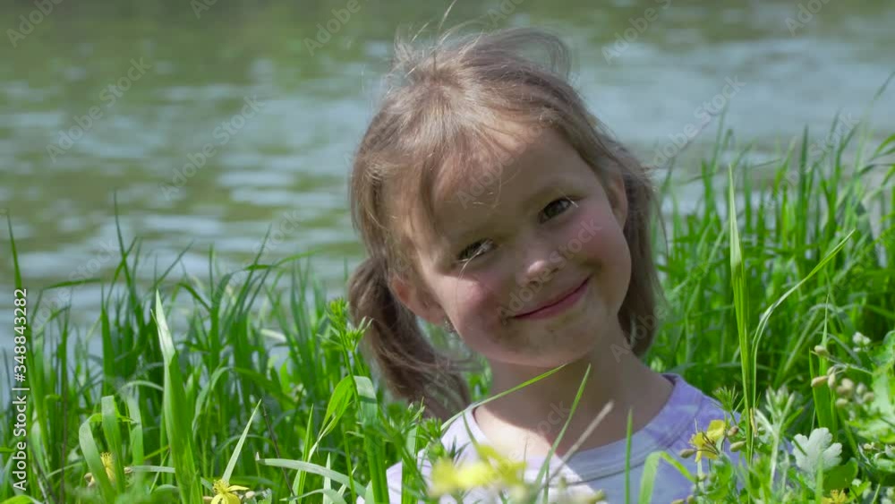 Portrait of a smiling little girl. Baby girl sitting in tall grass. Tiny kid have fun, enjoy nature outdoors. 4K Portrait of a smiling little girl. Baby girl sitting in tall grass. Tiny kid have fun, enjoy nature outdoors. 4K