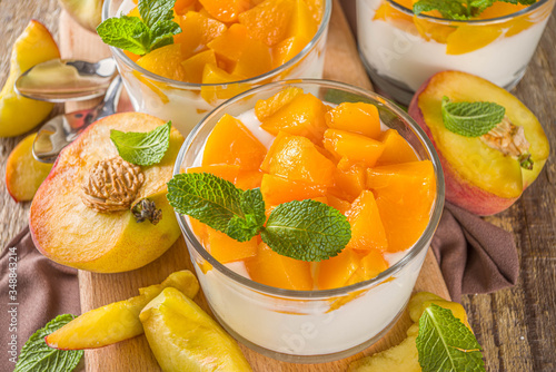 Curd or yogurt dessert with canned and fresh peaches, on wooden rustc background. Summer breakfast fruit dessert. photo