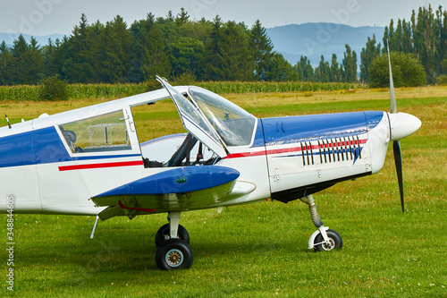 Side view of Zlin Z-43 four-seat light airplane standing on a grass runway. Low-wing monoplane.