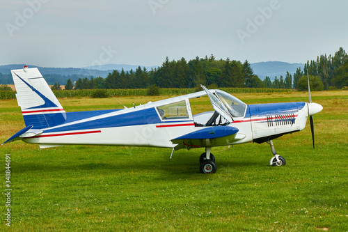 Side view of  Zlin Z-43 four-seat light airplane standing on a grass runway.  Low-wing monoplane.