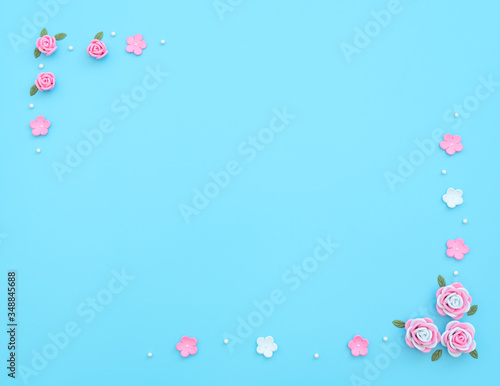 Pink and white flowers made of foamiran with green leaves and white beads on blue background. Mother day, Valentine day, Wedding, Birthday concept. Greeting or invitation card. Flat lay, copy space.