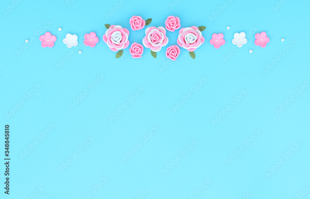 Pink and white flowers made of foamiran with green leaves and white beads on blue background. Mother day, Valentine day, Wedding, Birthday concept. Greeting or invitation card. Flat lay, copy space.