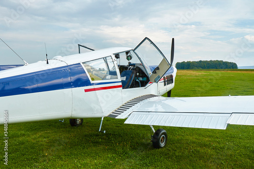 Closeup view of Zlin Z-43 four-seat airplane standing on a grass runway. Low-wing monoplane.