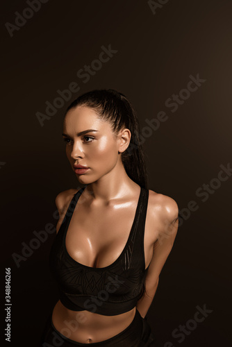 Sexy brunette sportswoman in sports top isolated on black