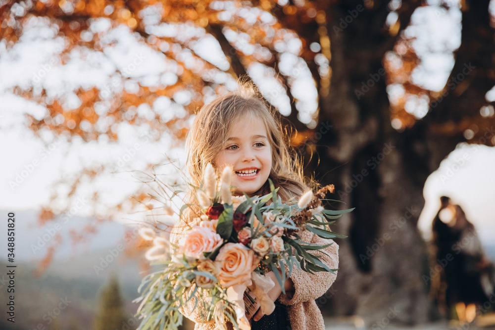 Portrait of a small stylish beautiful model girl who stands in the autumn mountains at sunset and holds a bouquet of flowers in her hands Portrait of a small stylish beautiful model girl who stands in the autumn mountains at sunset and holds a bouquet of flowers in her hands