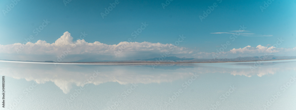 Blue Sky Clouds Mirror Reflection. Cloud Sky reflect on water surface of Bolivia's Salt Flats. Empty space in landscape. Holiday, vacation, freedom scene with horizon. Salar de Uyuni salt flat