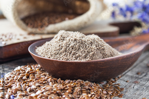 Crushed flax seed in a wooden spoon on a pile of flaxseed.