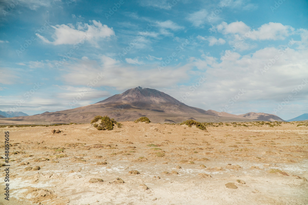 Dry, barren landscape mountain background.  Dramatic desert, snowcapped mountains wilderness. Mountain range view. Salt Flats of Uyuni, Bolivia. Copy space, blue sky, nature, hiking, and sand dust