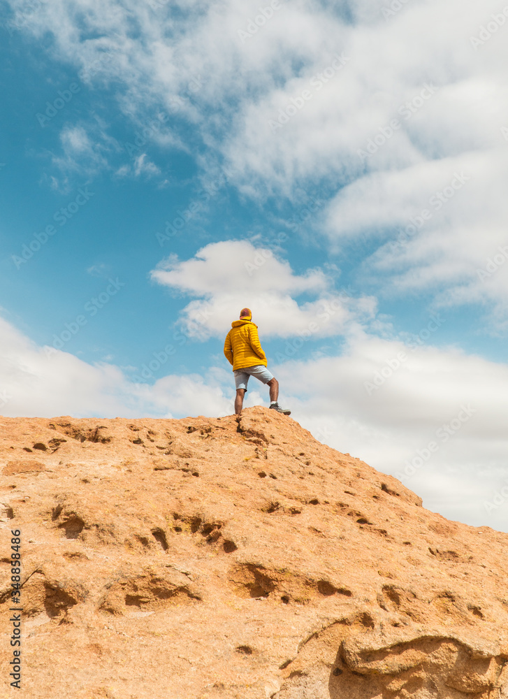 Tourist man hiking Rocky landscape mountain background. Dry, Barren desert, snowcapped mountains wilderness. Mountain range view. Salt Flats, Uyuni, Bolivia. Copy space, Rocks, blue sky, nature, hiker