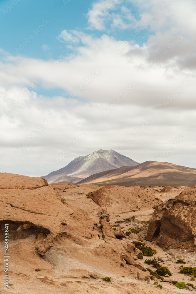 Naklejka premium Rocky landscape mountain background. Dry, Barren desert, snowcapped mountains wilderness. Mountain range view. Salt Flats of Uyuni, Bolivia. Copy space, Rocks, blue sky, nature, hiking, sand dust