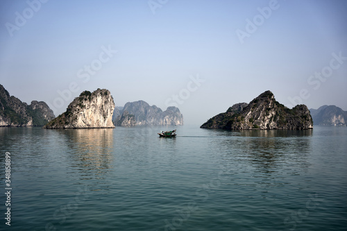 Small fishing boat between the rock formations on the Ha Long Bay, Vietnam.