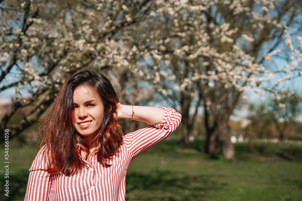 Portrait of a young girl with long hair walking in an Apple orchard in early spring, a blooming Apple tree with white flowers. Ecology, care Portrait of a young girl with long hair walking in an Apple orchard in early spring, a blooming Apple tree with white flowers. Ecology, care