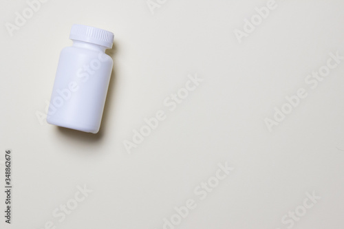 White plastic medical container for pills on left side of yellow background with copy space