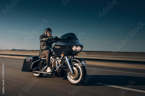 Motorcycle driver riding alone on asphalt motorway. Biker in the motion at the empty road. Rider go fast at the autobahn 