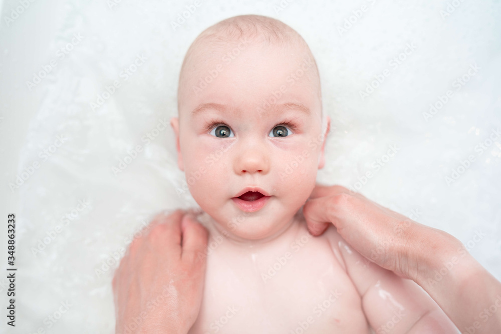 Adorable bath boy. Newborn baby bathing. Caring mother's hands. Hygiene and care for young children. Top view. Adorable bath boy. Newborn baby bathing. Caring mother's hands. Hygiene and care for young children. Top view.