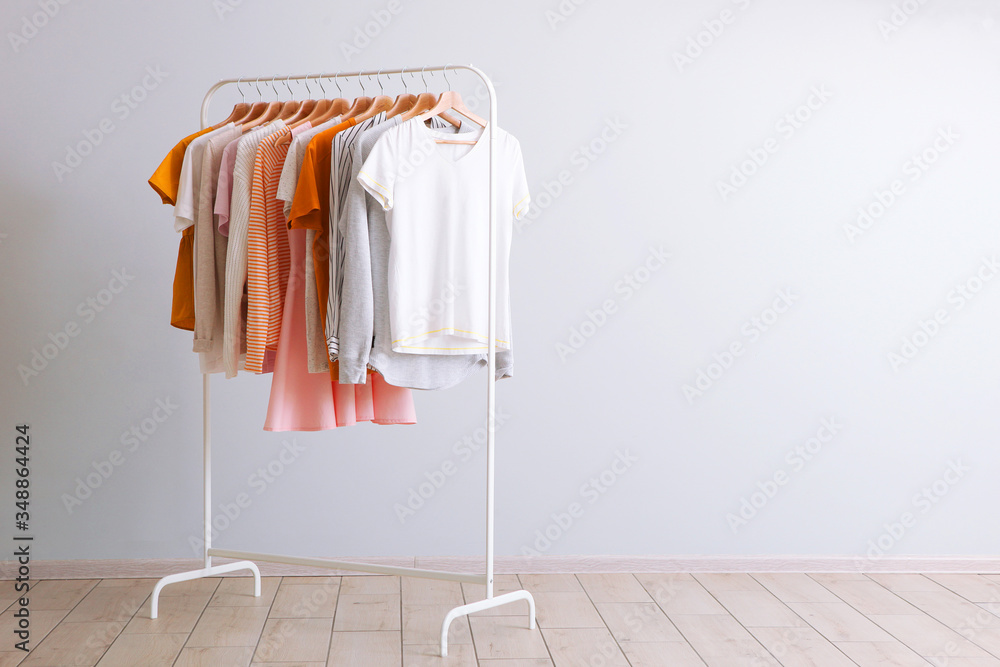fashion clothes on a rack in a light background indoors. place for text - obrazy, fototapety, plakaty 