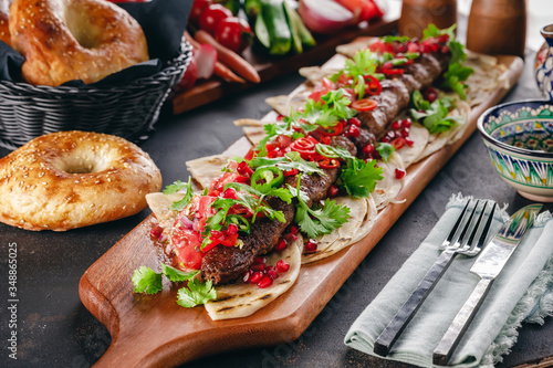 Lula Kebab on the wooden service plank with garnet and arabic bread