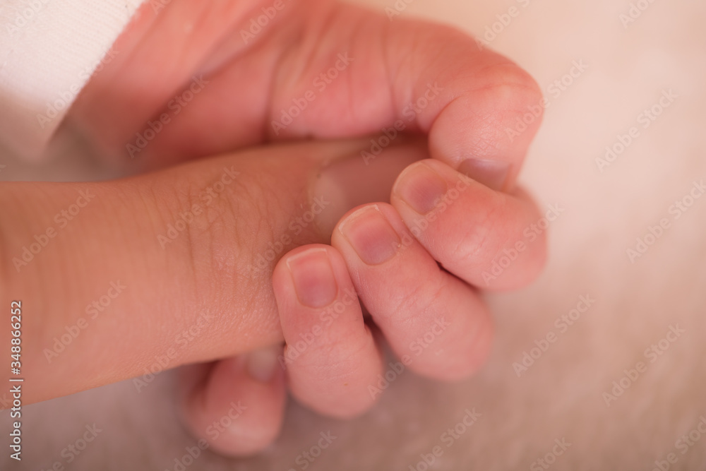 Touch of love. Close-up of baby's hand holding mother's finger. Newborn baby holding mother's hand, image with shallow depth of field. Touch of love. Close-up of baby's hand holding mother's finger. Newborn baby holding mother's hand, image with shallow depth of field.