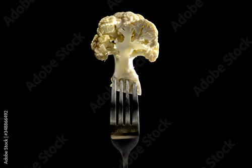 Cauliflower on a fork in black background . close up . vegetable Vegetarian and vegan concept.