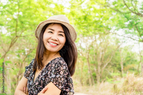 beautiful asian woman age 40s wearing a hat and smiling outdoors in green park