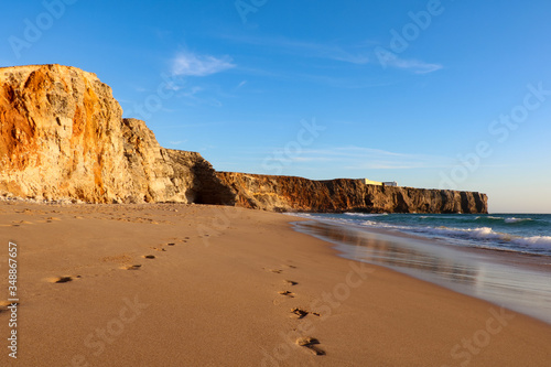 Footprints left in the sand on a beach in Algarve, Portugal during the sunset.