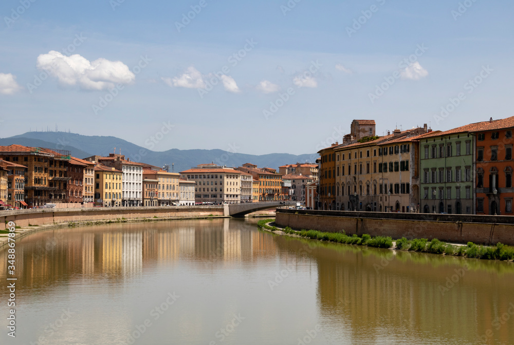 A view of Arno river in Florence, Italy, with pastel townhouses on both sides reflecting in the water.
