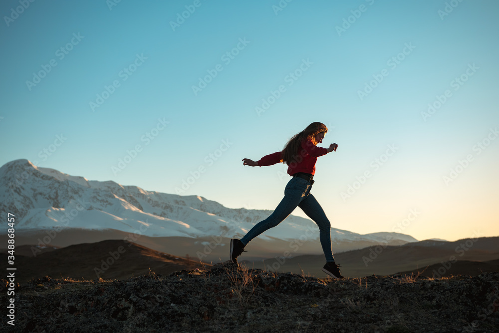 Slim sporty girl walks at sunset in mountains Slim sporty girl walks at sunset in mountains