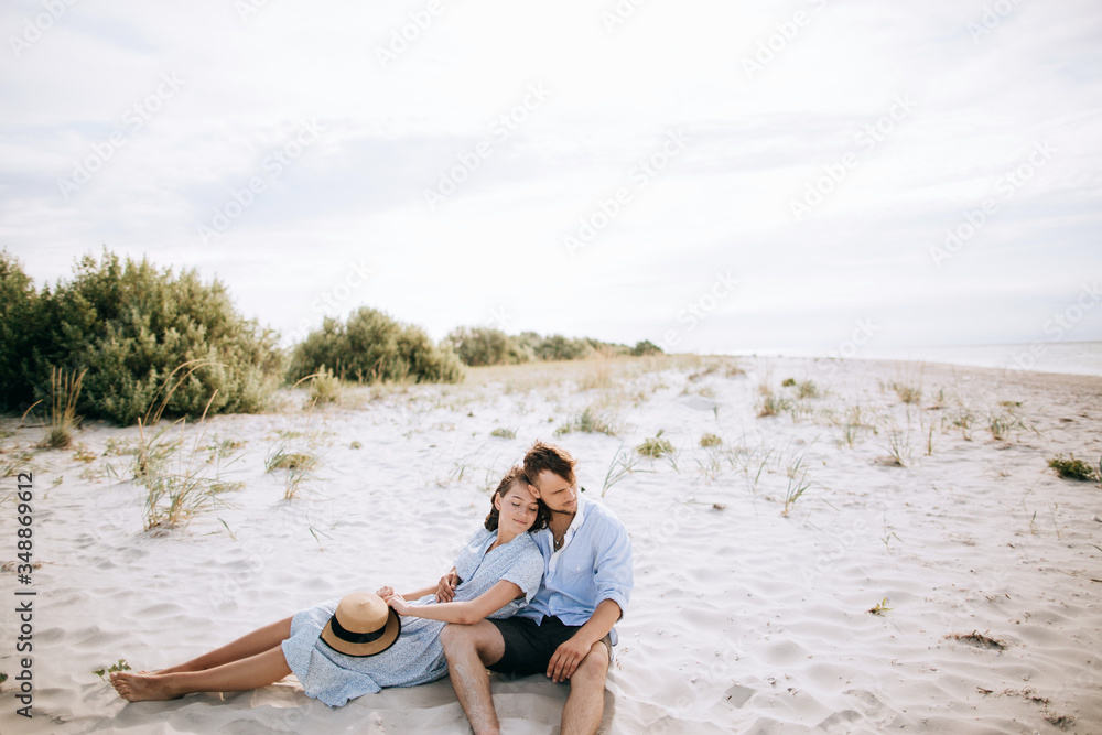 Couple sitting on the beach on the sand and dreaming.
