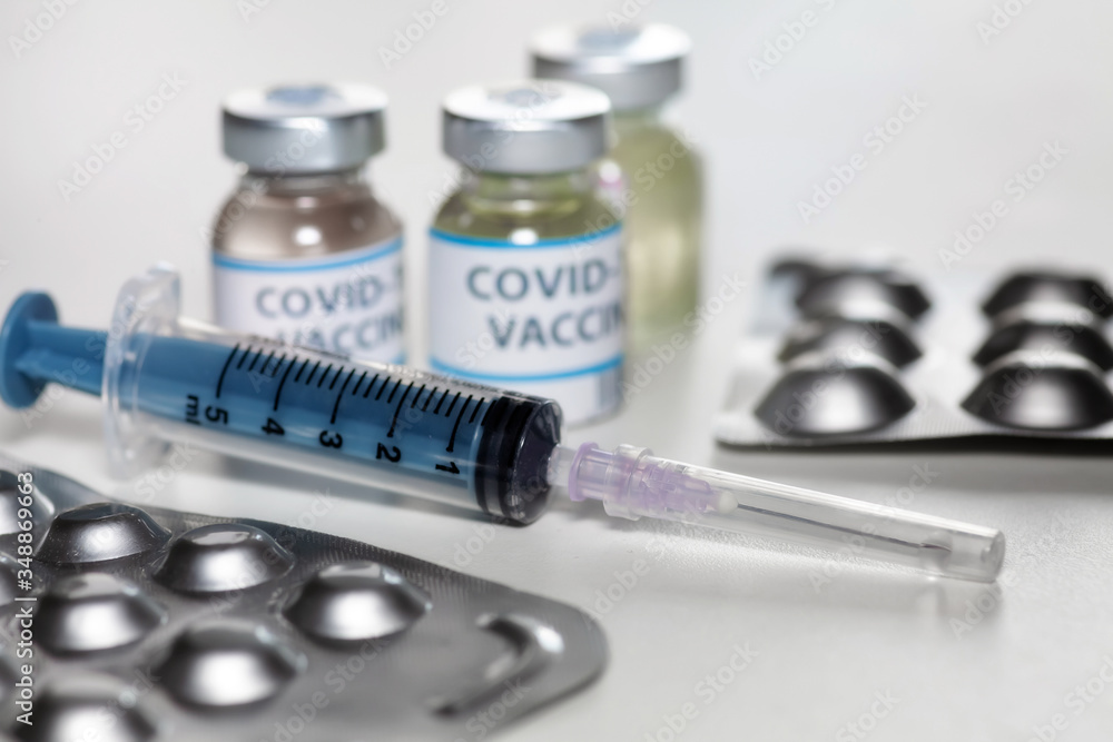 Injection syringe with vaccine bottles and medicine in selective focus for treatment of COVID-19 patients Injection syringe with vaccine bottles and medicine in selective focus for treatment of COVID-19 patients